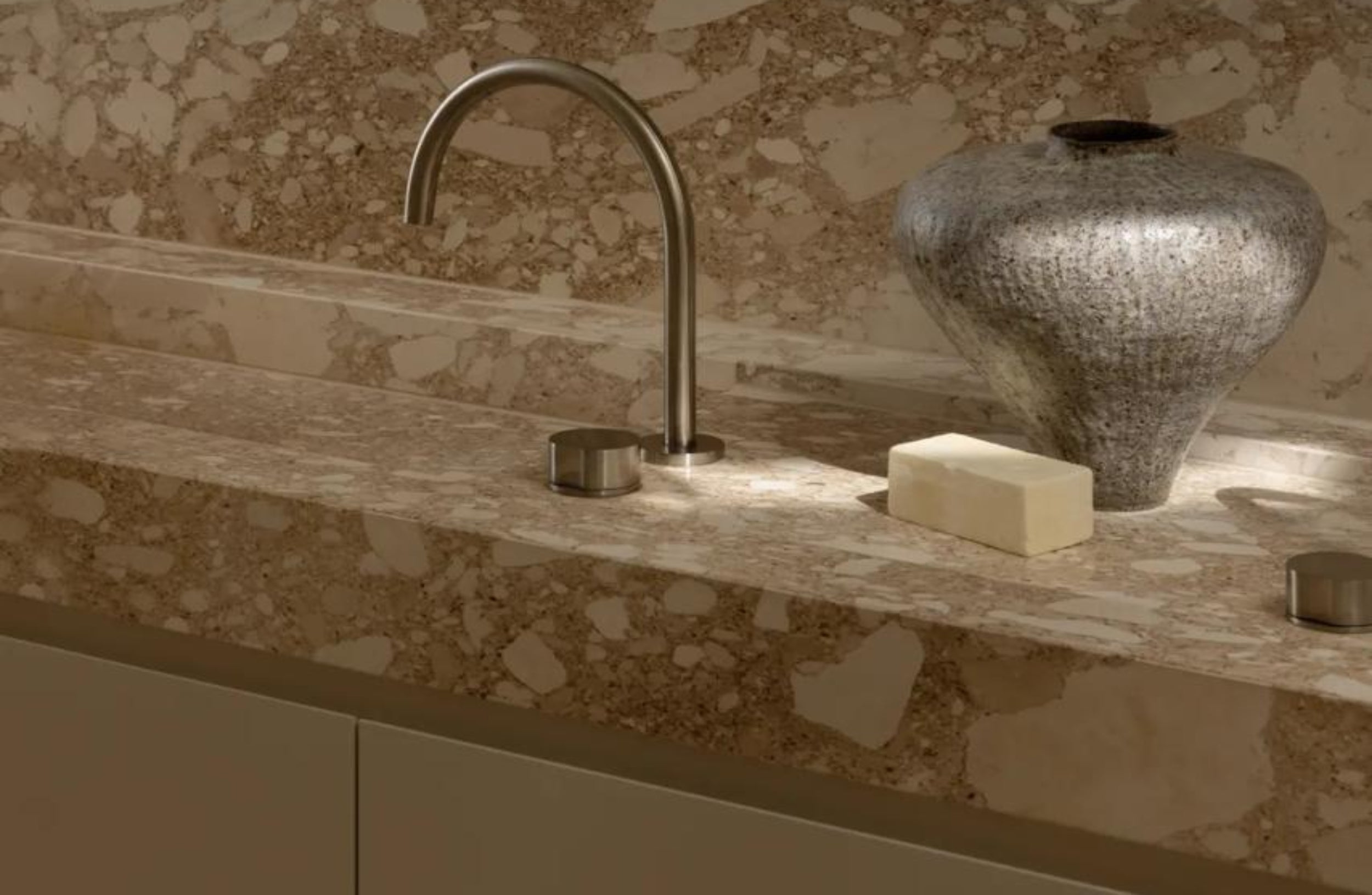 Bathroom vanity with marble countertop, faucet, soap, and decorative vase.