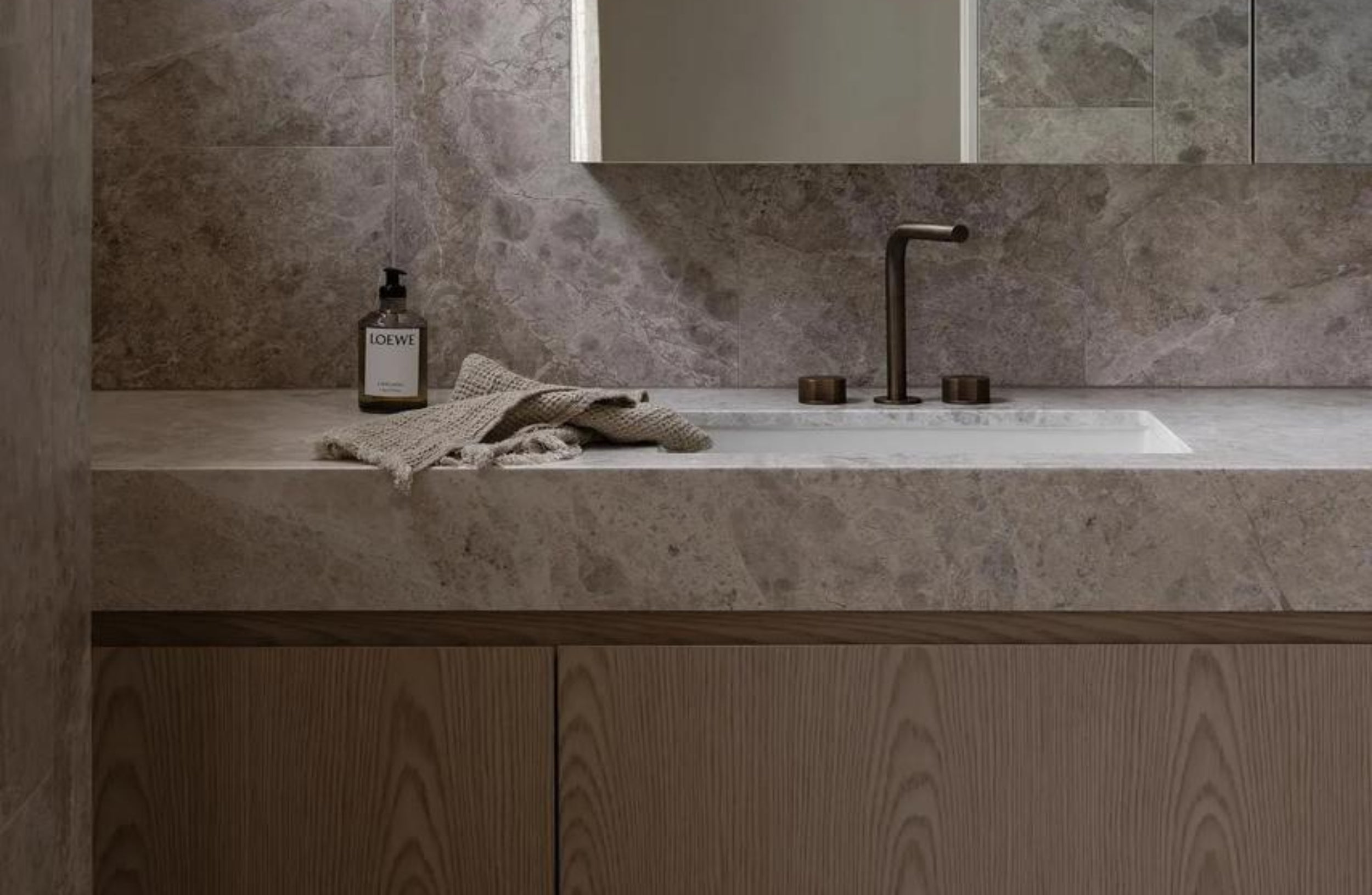 Bathroom vanity with marble countertop, mirror, and lighting fixture.